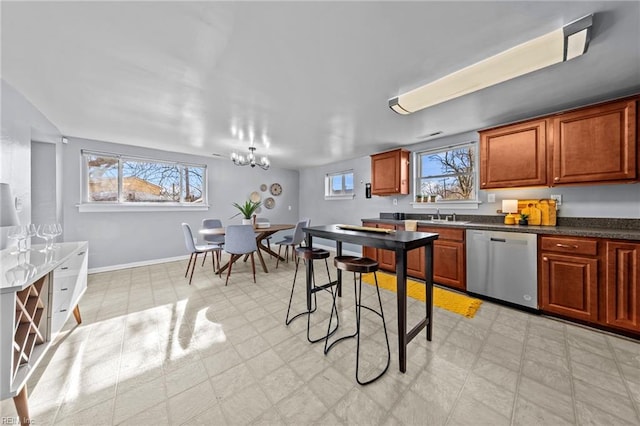 kitchen featuring brown cabinets, dark countertops, stainless steel dishwasher, baseboards, and light floors