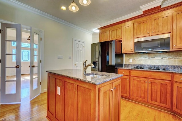 kitchen with black appliances, brown cabinetry, and dark stone counters