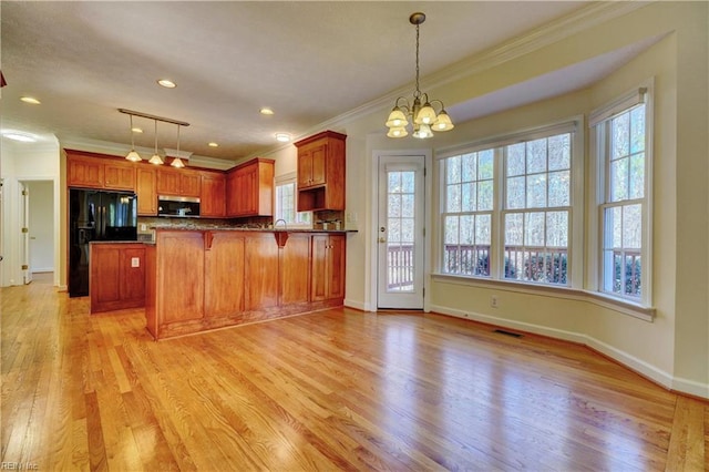 kitchen with visible vents, crown molding, stainless steel microwave, light wood-type flooring, and black fridge