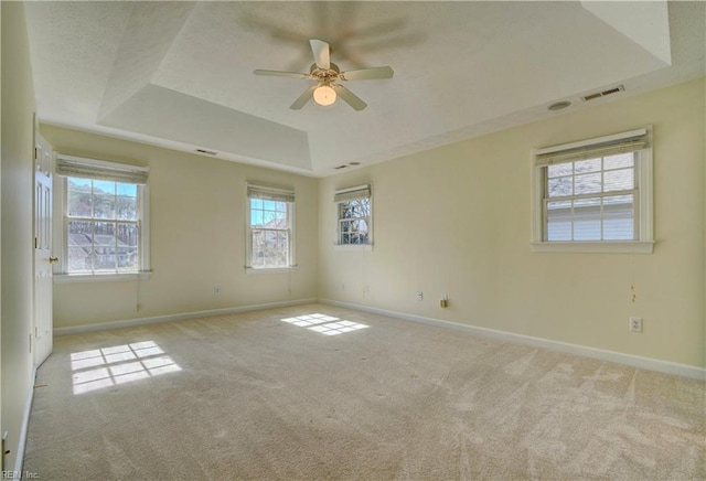 spare room with a raised ceiling, baseboards, visible vents, and carpet floors