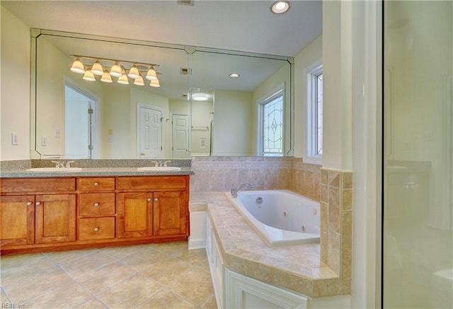 bathroom with a sink, a tub with jets, double vanity, and tile patterned flooring