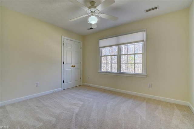 spare room with carpet, visible vents, and baseboards