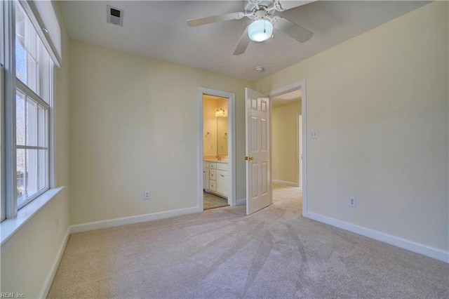 unfurnished bedroom with visible vents, baseboards, light carpet, and ensuite bathroom