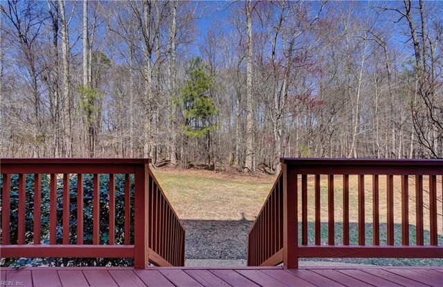 wooden deck with a lawn and a forest view