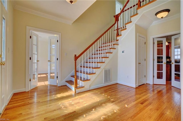 interior space featuring visible vents, french doors, crown molding, and wood finished floors