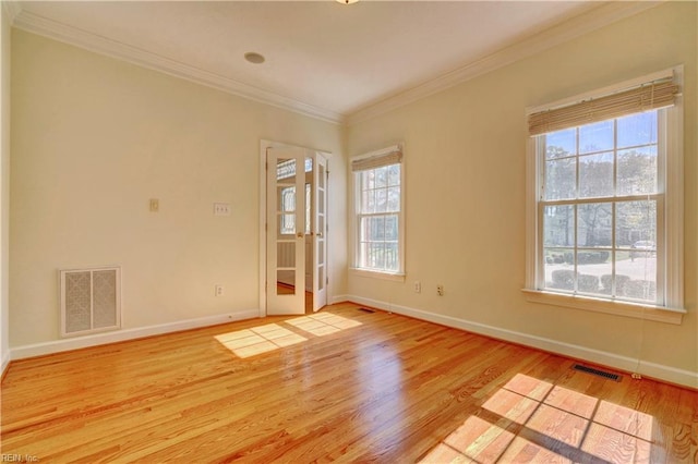 spare room featuring visible vents, plenty of natural light, light wood-style flooring, and crown molding