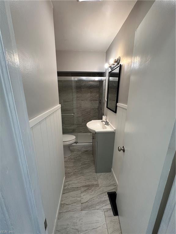 full bath featuring a wainscoted wall, toilet, a stall shower, marble finish floor, and vanity