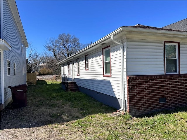 view of side of home with crawl space, a lawn, entry steps, and brick siding