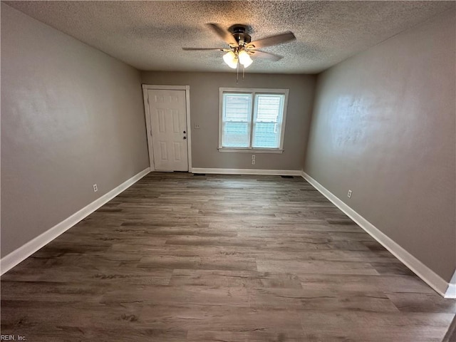 spare room with dark wood-type flooring, a ceiling fan, baseboards, and a textured ceiling