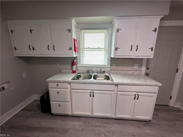 kitchen with white cabinetry, light countertops, wood finished floors, and a sink