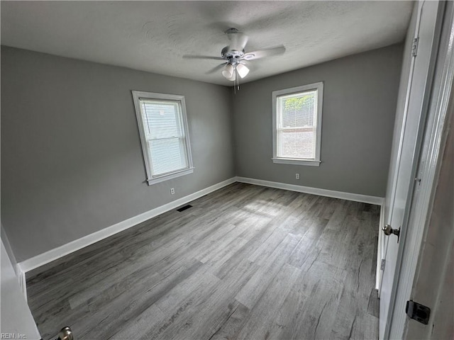 empty room with visible vents, baseboards, a textured ceiling, and wood finished floors