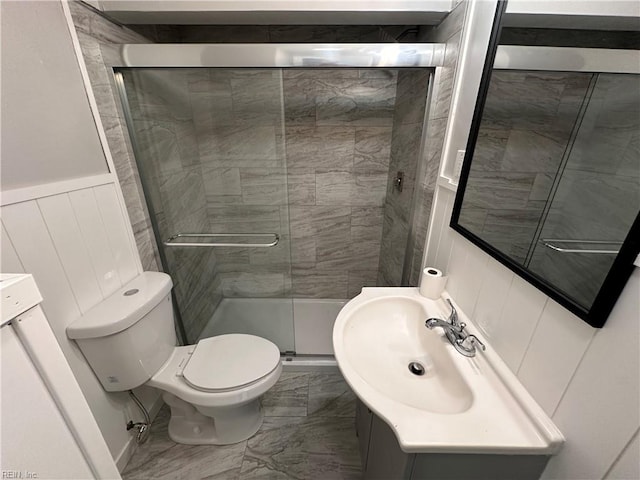 full bath with vanity, a wainscoted wall, a stall shower, toilet, and marble finish floor