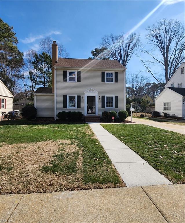 colonial inspired home featuring a front lawn and a chimney