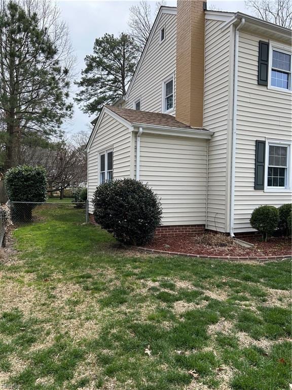 view of home's exterior with a yard, a chimney, and fence