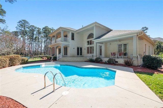 rear view of property featuring a balcony, a ceiling fan, an outdoor pool, french doors, and a patio area