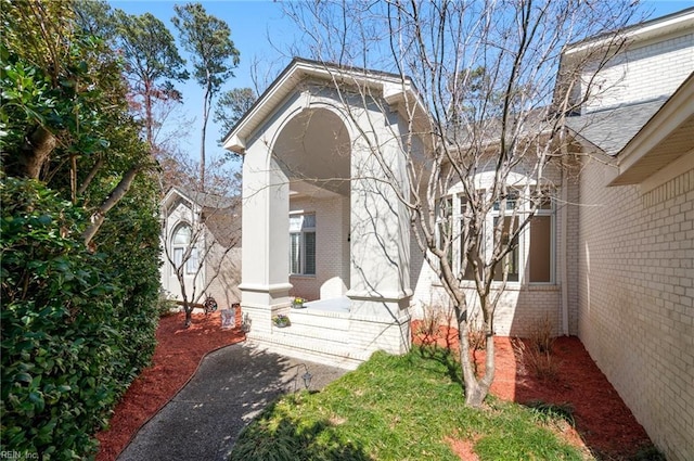 view of exterior entry with covered porch and brick siding