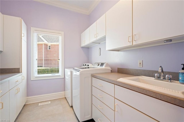 clothes washing area with a sink, cabinet space, crown molding, light tile patterned floors, and washing machine and clothes dryer