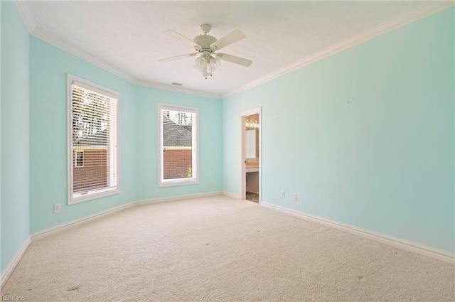 spare room featuring visible vents, crown molding, baseboards, carpet flooring, and a ceiling fan