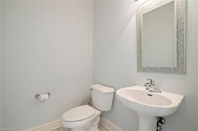 bathroom with toilet, baseboards, and a sink