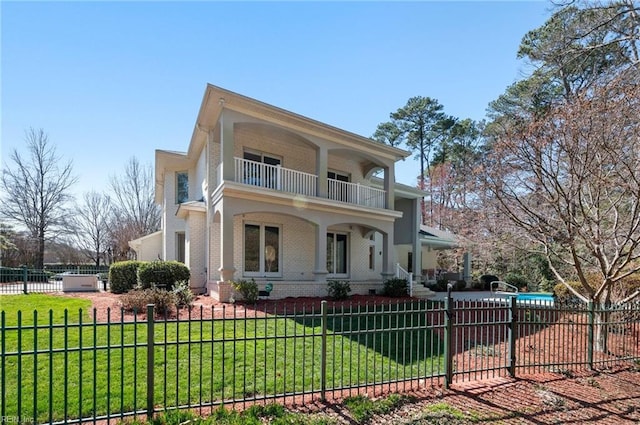 view of front of home with a fenced front yard, a front lawn, brick siding, and a balcony