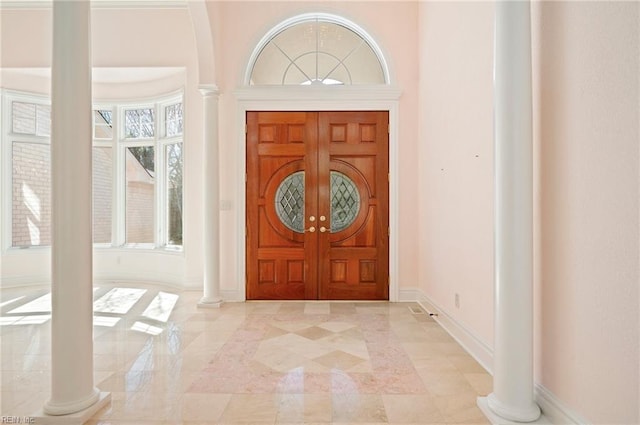 foyer featuring baseboards and decorative columns