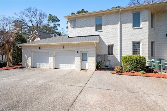 view of home's exterior with an attached garage, fence, brick siding, and driveway