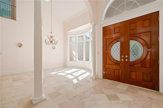 foyer with crown molding, baseboards, a notable chandelier, high vaulted ceiling, and ornate columns