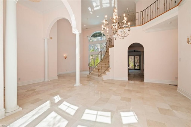 foyer entrance featuring stairway, baseboards, a high ceiling, arched walkways, and crown molding