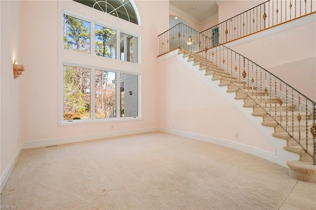 interior space with stairway, crown molding, a high ceiling, and baseboards