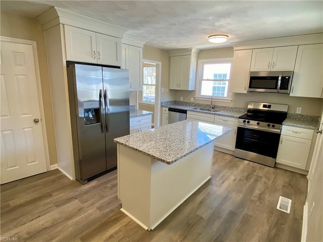 kitchen with visible vents, a sink, a center island, appliances with stainless steel finishes, and light wood finished floors