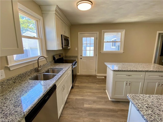 kitchen featuring white cabinets, stainless steel appliances, light wood-type flooring, and a sink