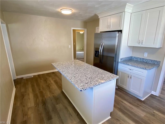 kitchen featuring dark wood-type flooring, a center island, white cabinets, stainless steel fridge with ice dispenser, and light stone countertops