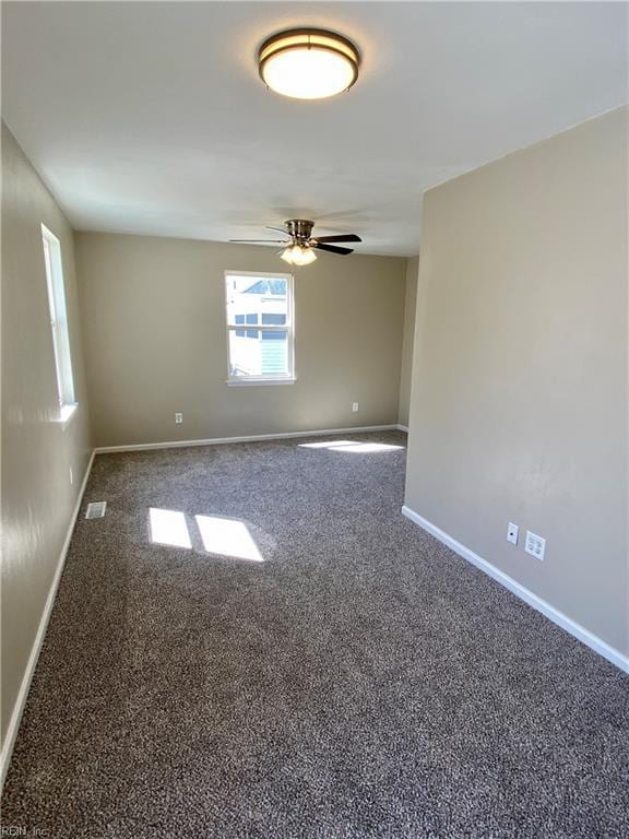 carpeted spare room featuring visible vents, ceiling fan, and baseboards