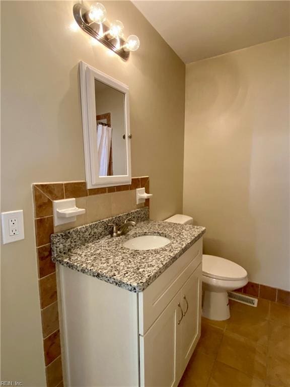 full bath with visible vents, tile walls, toilet, tile patterned floors, and vanity