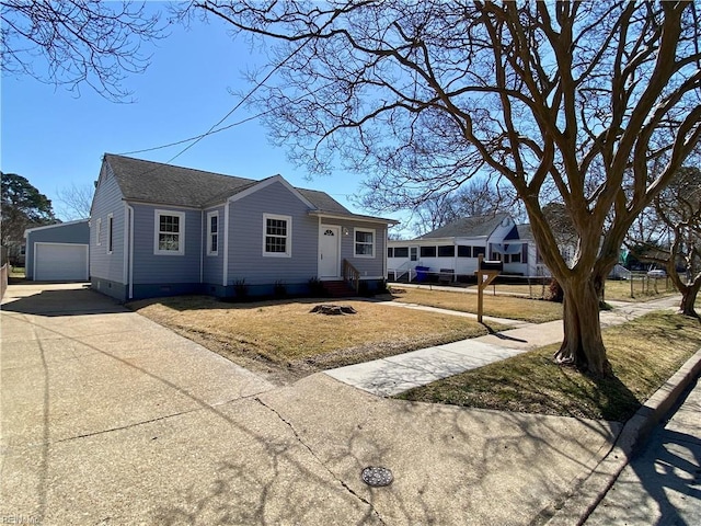 view of front facade with an outbuilding, a front lawn, entry steps, a detached garage, and roof with shingles