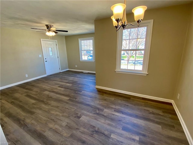 empty room featuring ceiling fan with notable chandelier, baseboards, and dark wood-style flooring