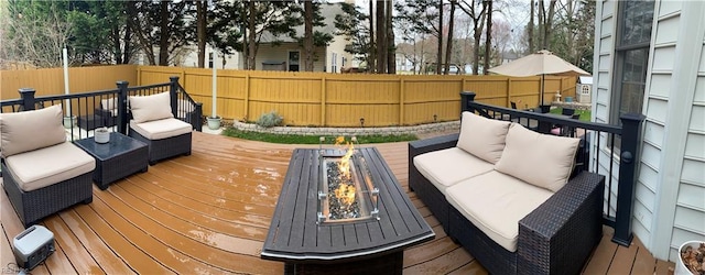 wooden deck with an outdoor living space with a fire pit and a fenced backyard