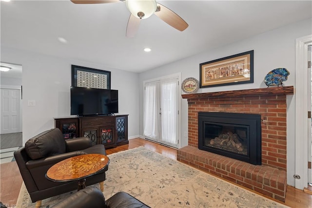 living room featuring baseboards, ceiling fan, recessed lighting, a fireplace, and wood finished floors