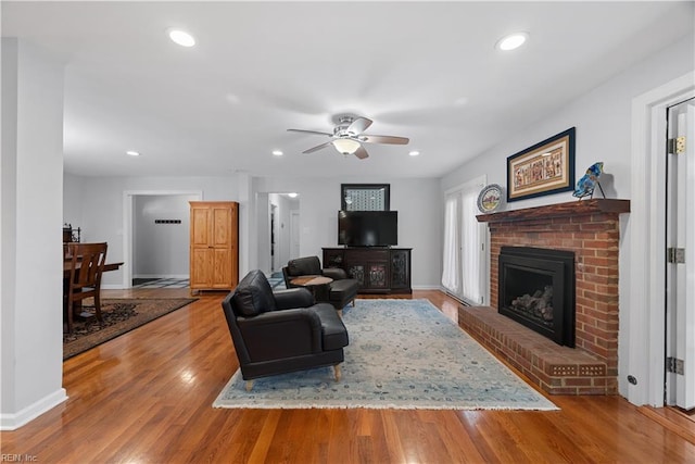 living room with a brick fireplace, recessed lighting, wood finished floors, and baseboards