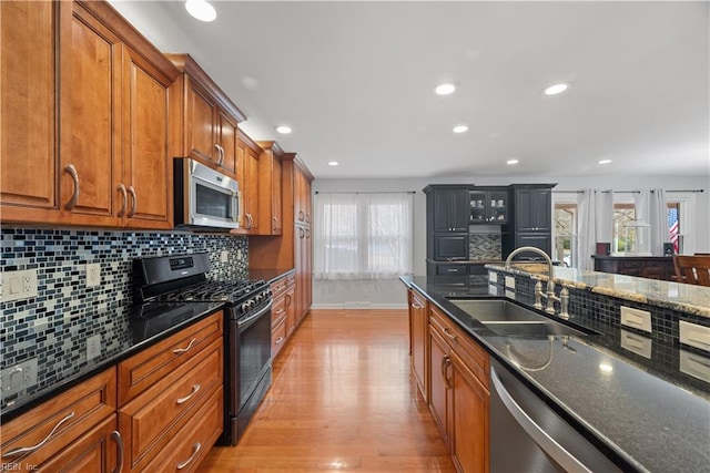 kitchen with a sink, stainless steel appliances, brown cabinets, and light wood-style flooring