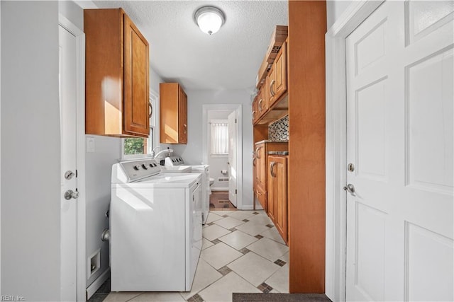 clothes washing area featuring cabinet space, a textured ceiling, and washing machine and clothes dryer