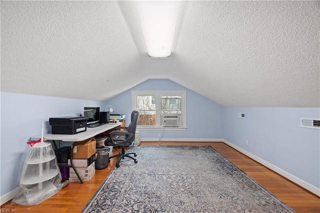 office space featuring vaulted ceiling, wood finished floors, baseboards, and a textured ceiling