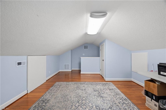 additional living space featuring vaulted ceiling, visible vents, and wood finished floors