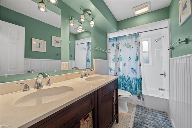 bathroom featuring a sink, toilet, shower / bathtub combination with curtain, and wainscoting