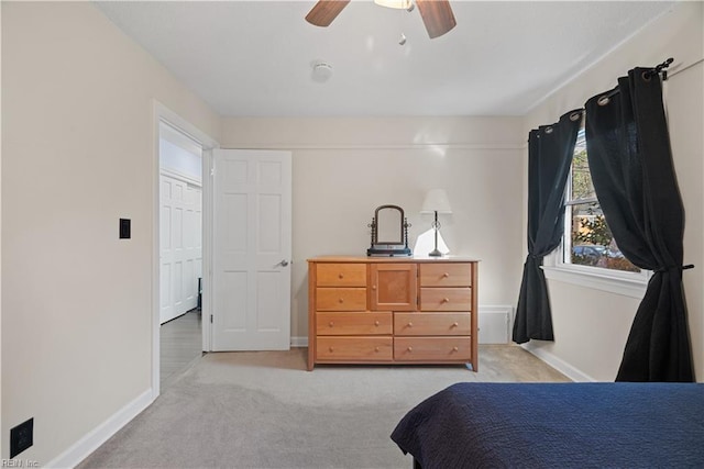 bedroom featuring light colored carpet, baseboards, and ceiling fan