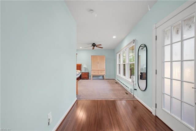 corridor with a baseboard heating unit, hardwood / wood-style flooring, recessed lighting, and baseboards