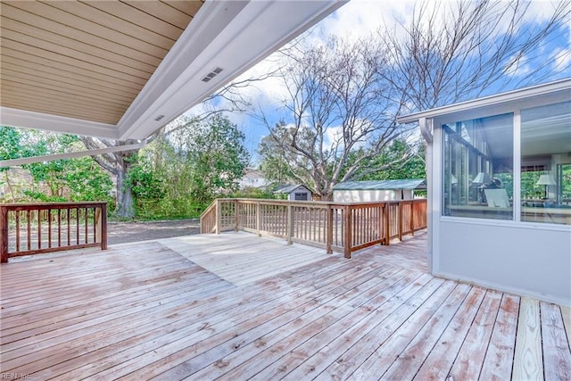 wooden deck featuring a shed, an outdoor structure, and a sunroom