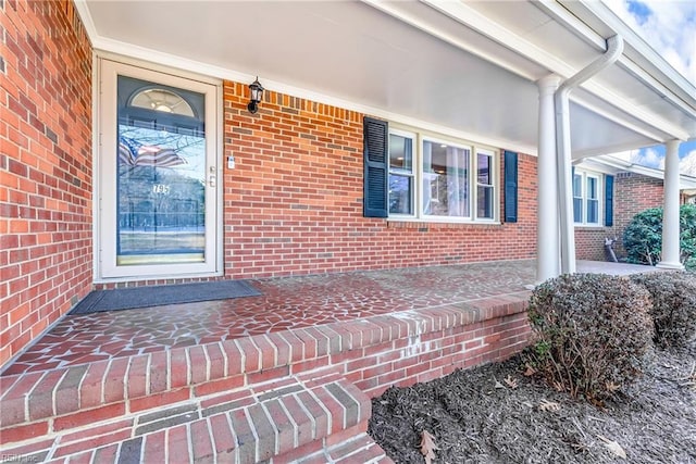 entrance to property featuring brick siding and covered porch