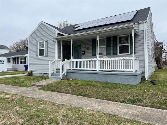 bungalow-style house featuring a porch, a front lawn, and roof mounted solar panels