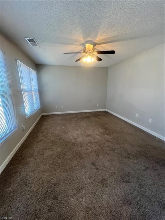 empty room featuring visible vents, ceiling fan, baseboards, and dark colored carpet